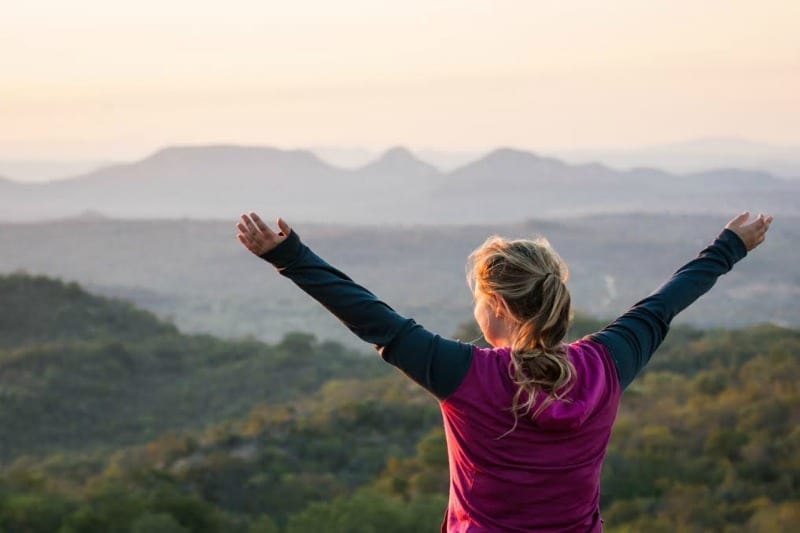 girl with arms outstretched looking at mountain view