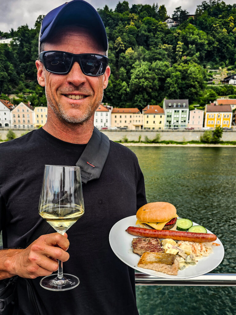 Man holding a glass of wine and plate of food