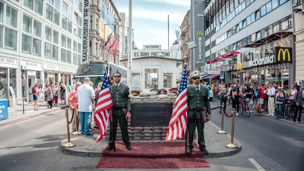 two us soldiers standing outside Checkpoint Charlie in the middle of a road