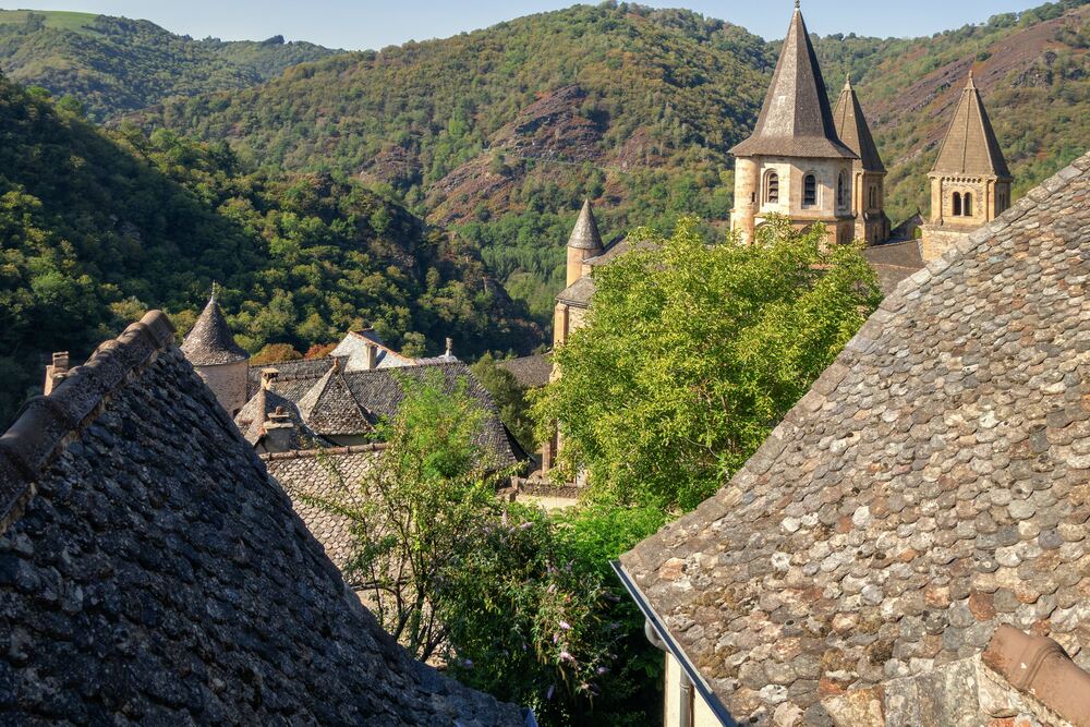 rooftops pf Conques Abbey in front of mountains