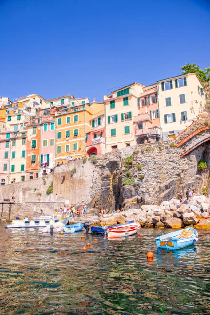 colored buildings of riomaggiore with small boats in water in foreground