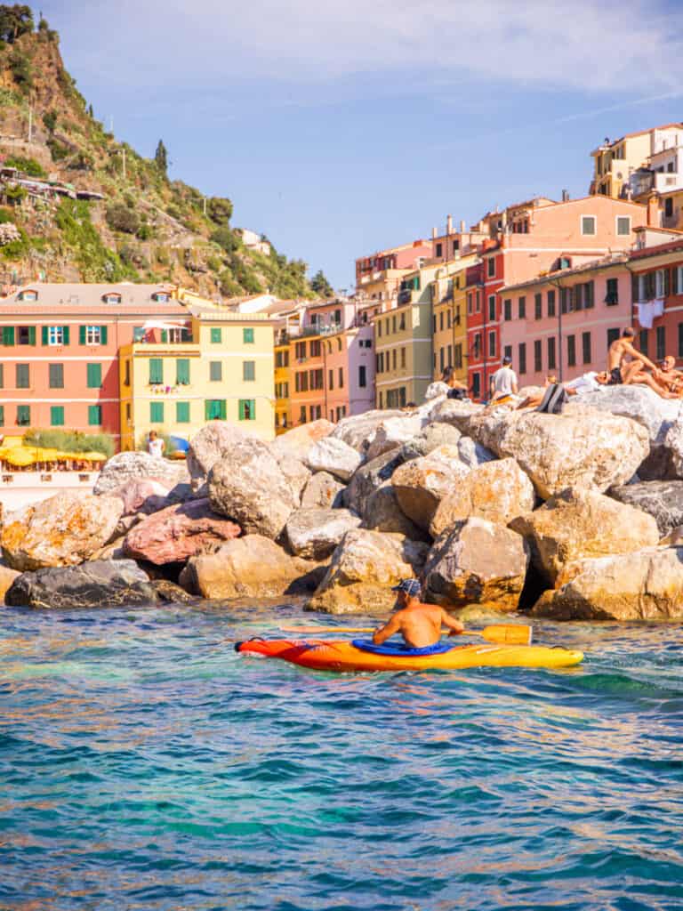 person on kayak in front of colored houses cinque terre