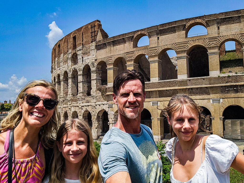 Family of four posing for a photo in front of the Colosseum in Rome