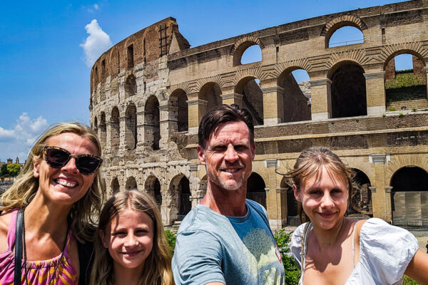 Family of four posing for a photo in front of the Colosseum in Rome