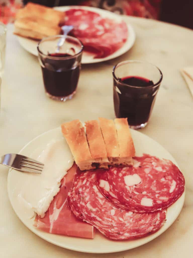 cured meats, bread and red wine on table