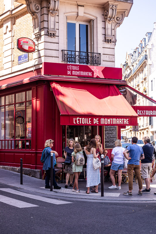 people standing outside l'etoile de montmartre restaurant on corner
