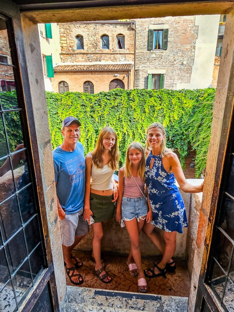 Family of four standing on Juliet's balcony in Verona