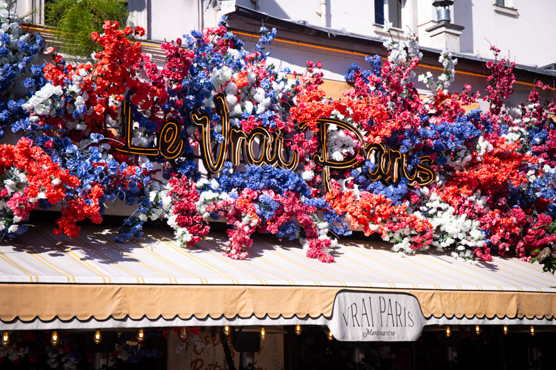 flowers on restaurant facade with words le vrai paris