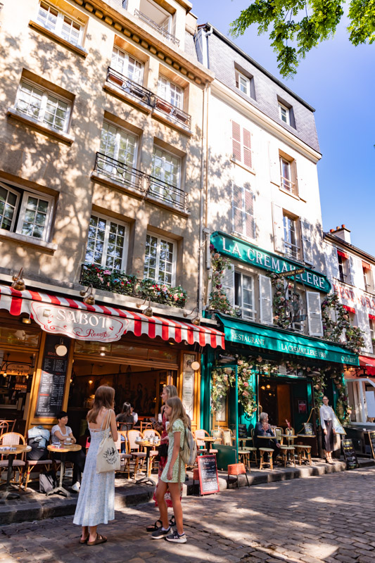 people standing outside colorful buildings in montmartre