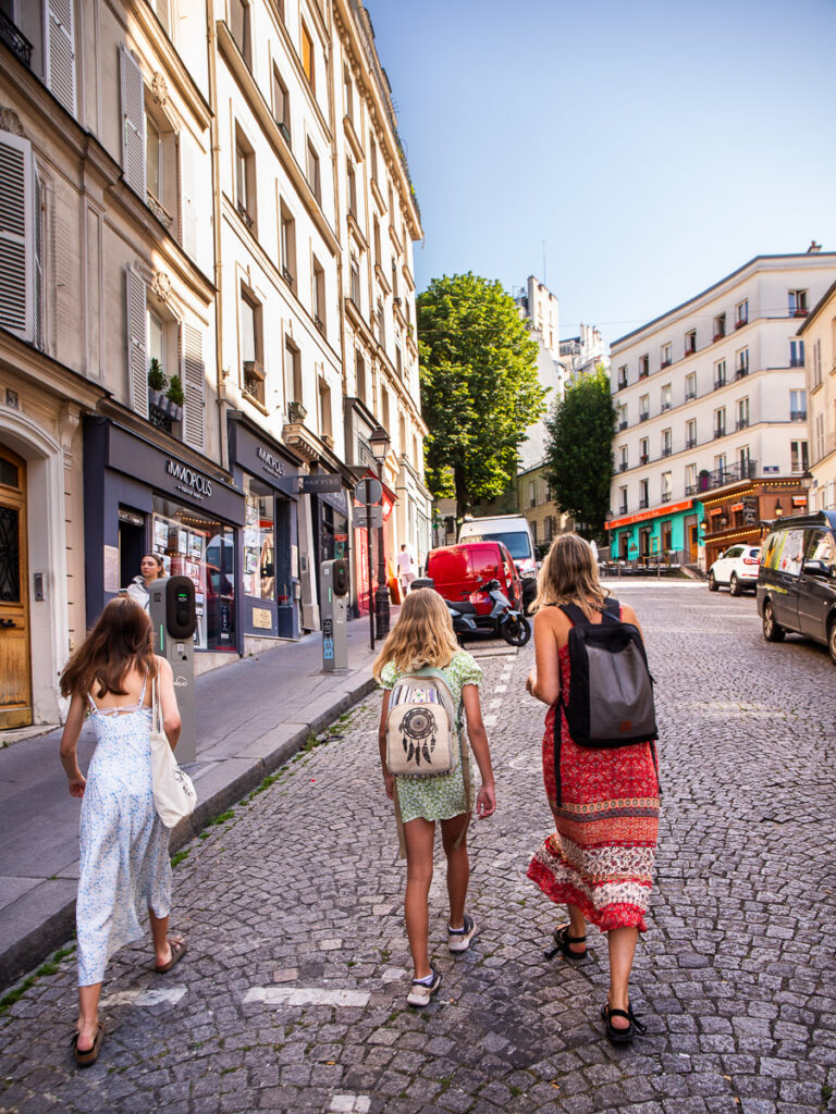 mum and two daughters waling on cobblestone street in paris
