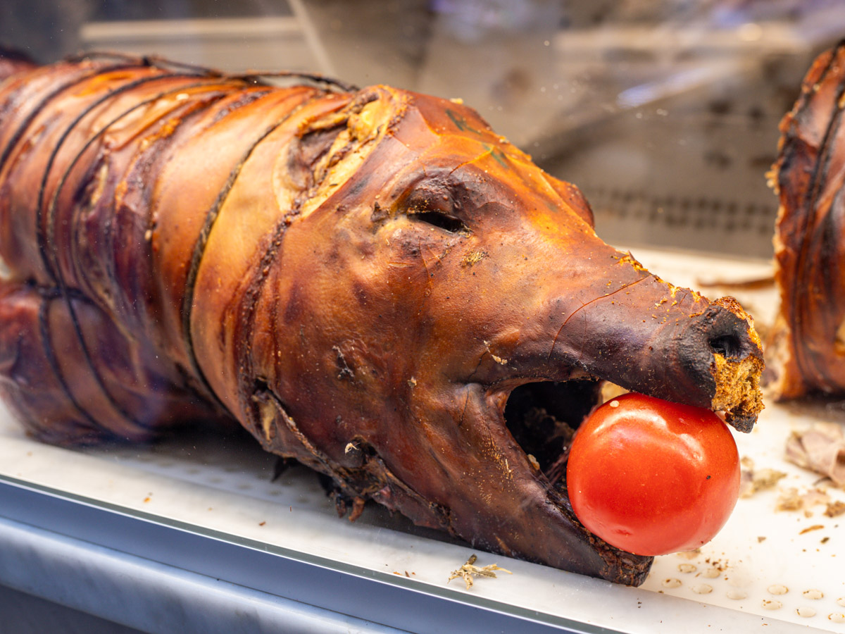 roasted pig in store window with tomato in mouth