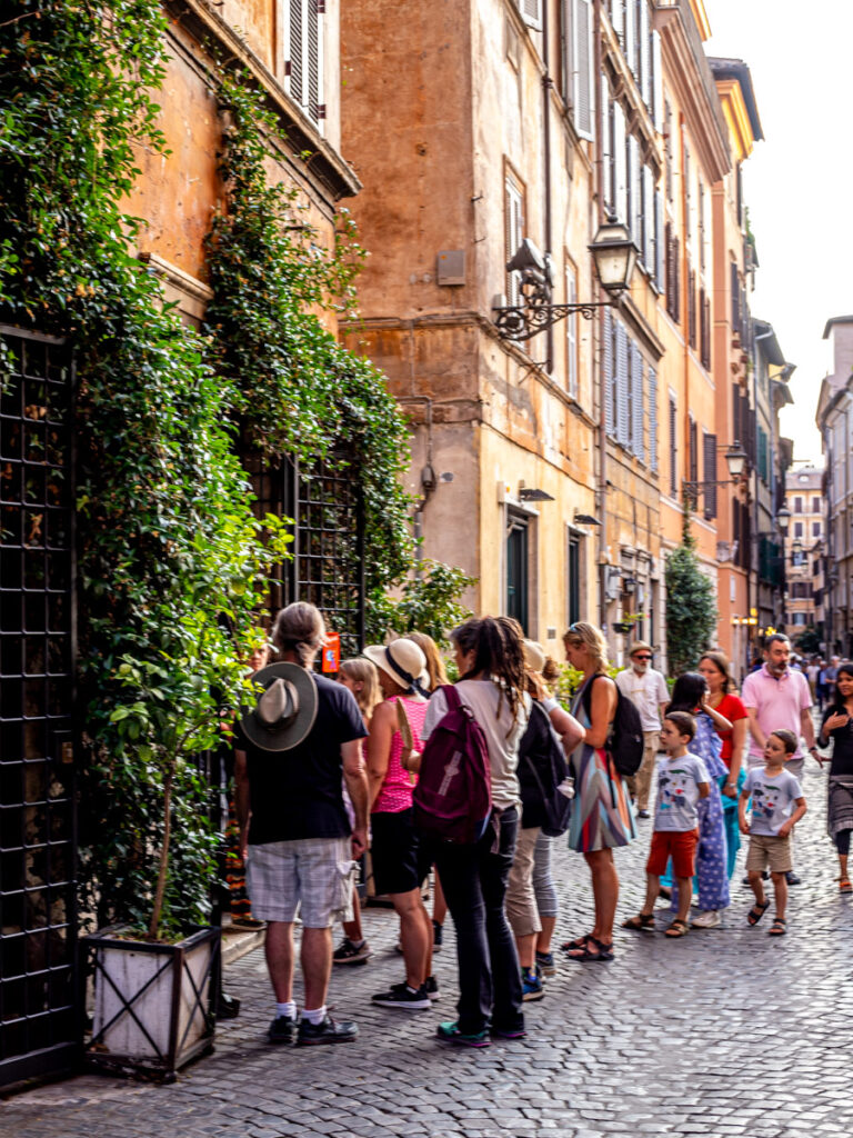 people standing outside ice cream shop on cobblestone street in rome