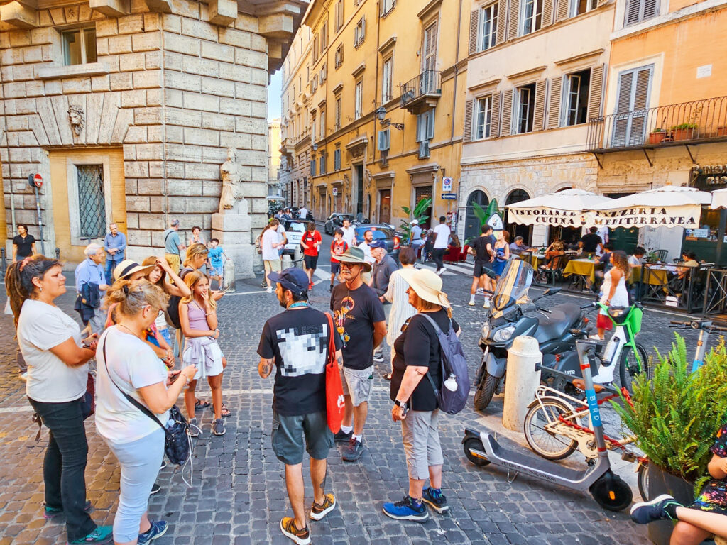 people standing around listening to tour guide on streets of rome