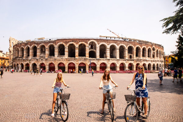 Mom and two daughters biking in front od a colosseum