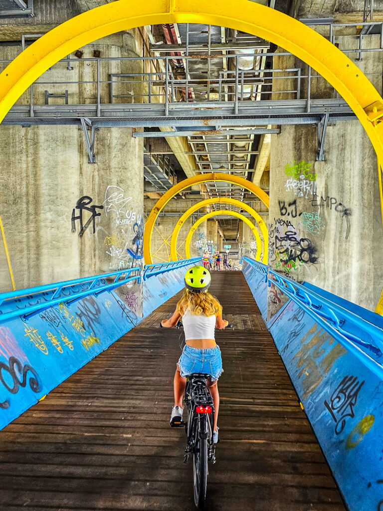 Girl riding a bike across a bridge