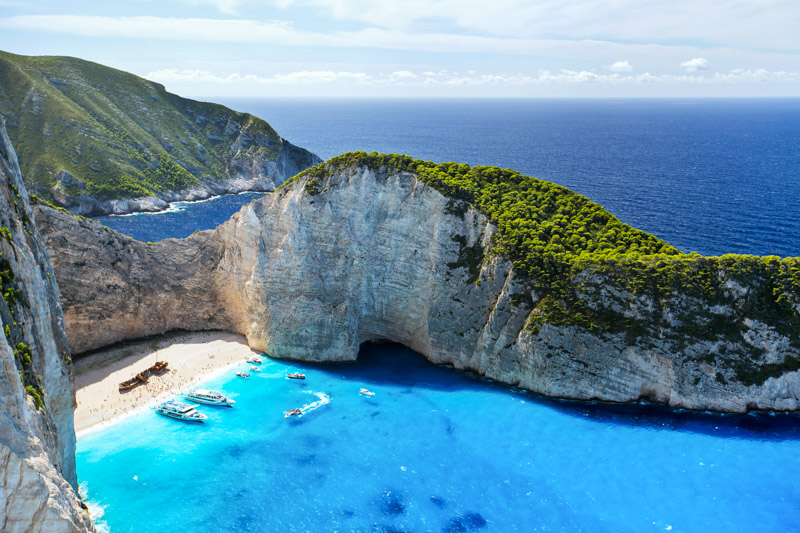 brilliant blue water of Most Incredible Navagio Beach or Shipwreck Beach. with boats moored