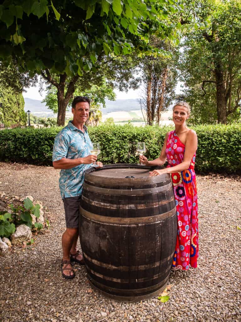 caz and craig standing around a wine barrel with tuscany view