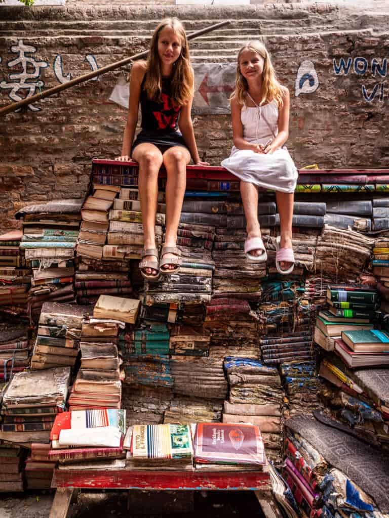 Kalyra and Savannah sitting on wall of books