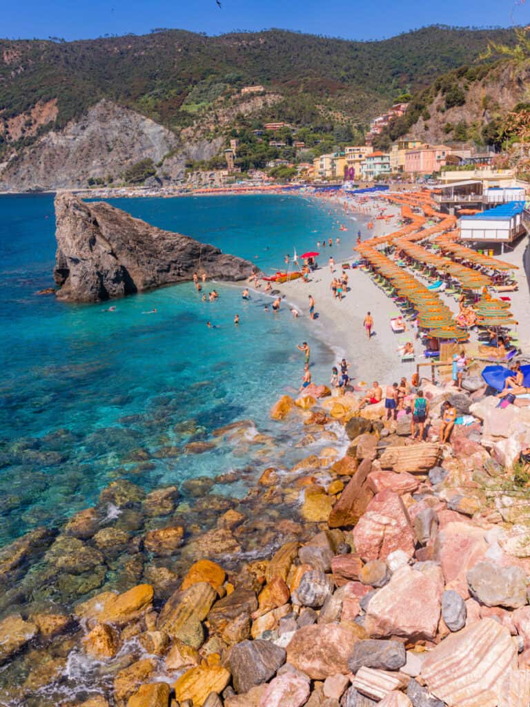 people sitting on the beaches of Monterosso al Mare with rock in the water