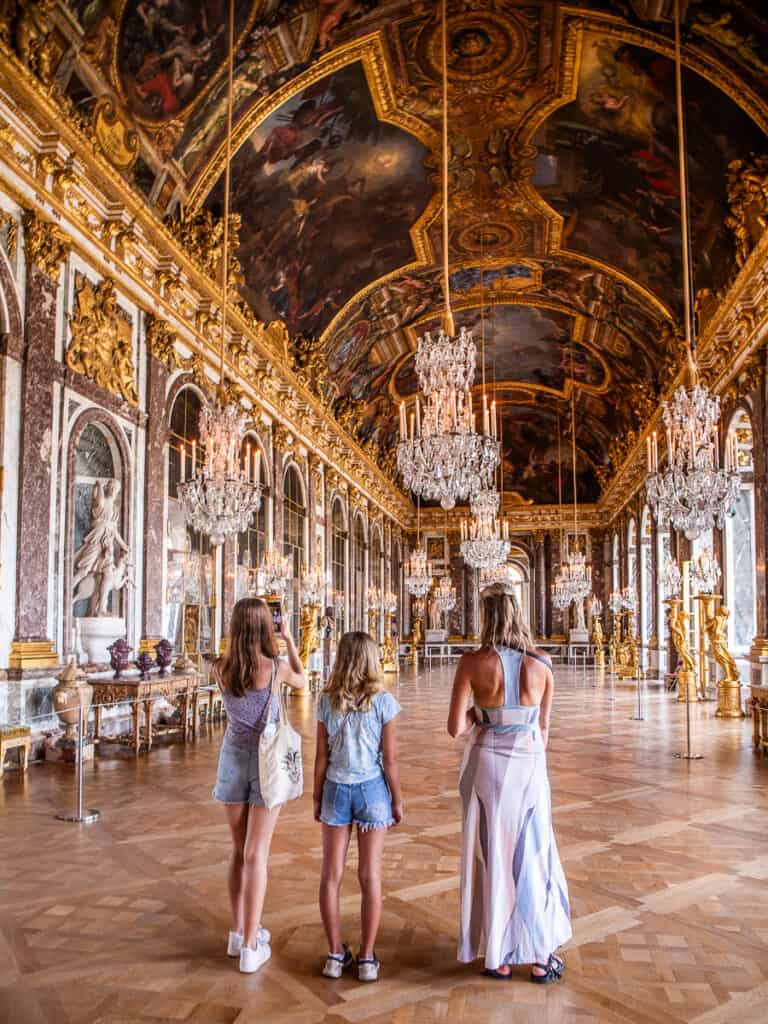 Caz and girls standing in hall of mirrors versaille