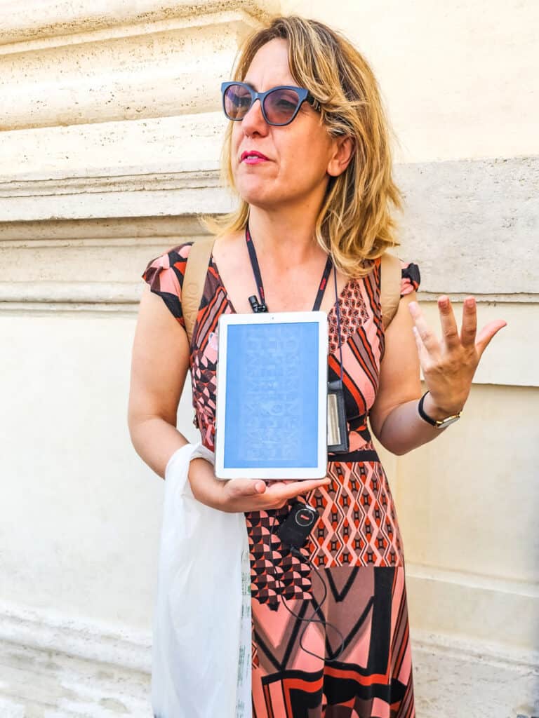 live tour guide holding ipad with pictures of sistine chapel