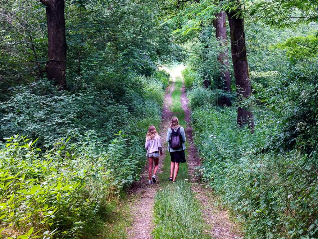 Mom and daughter walking a trail through the forest