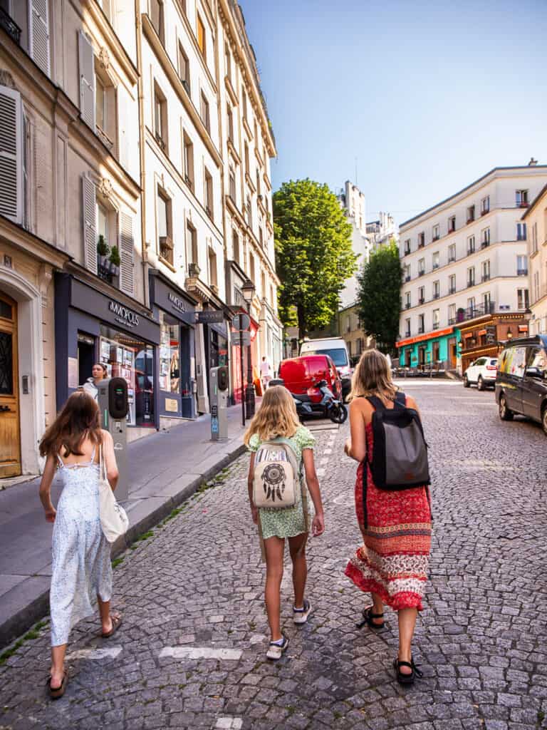 Mom and two daughters walking a cobblestone street in Paris