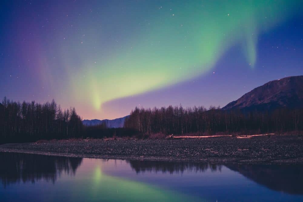 green northern lights in sky above lake