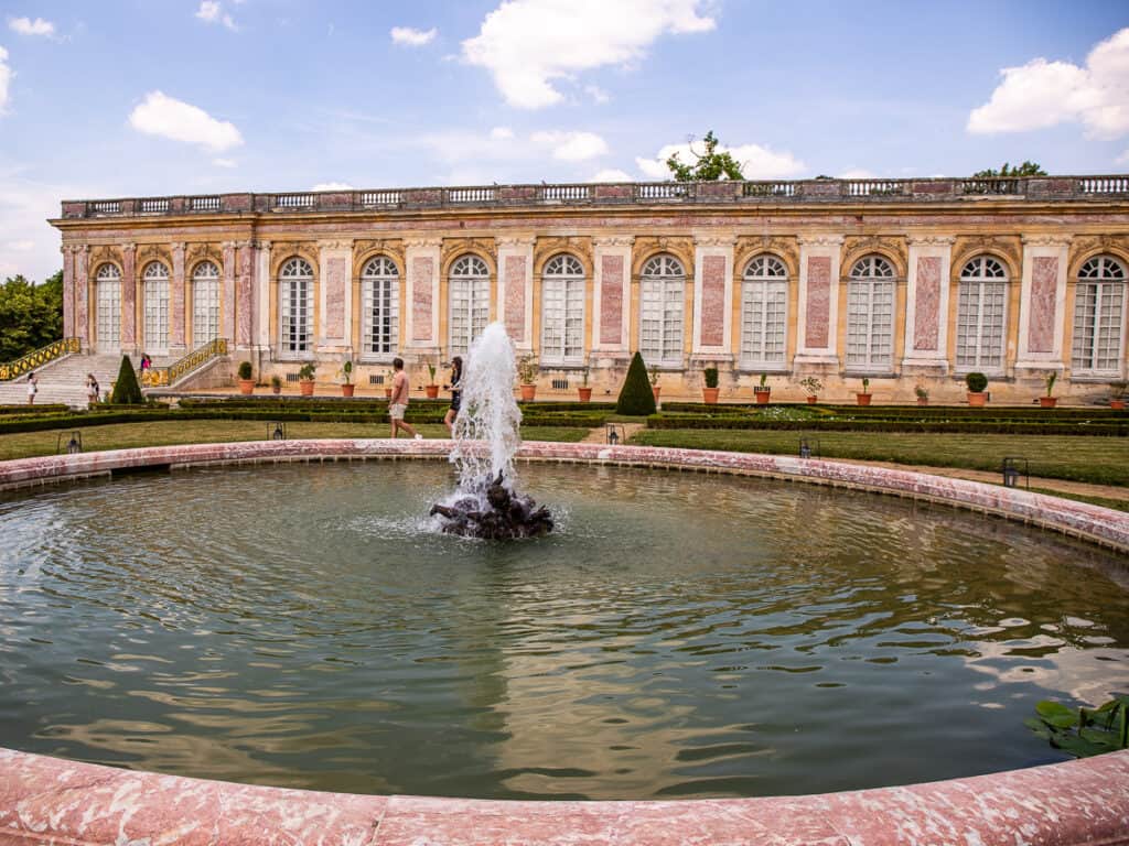 fountain in front of pink marble building of grand trianon