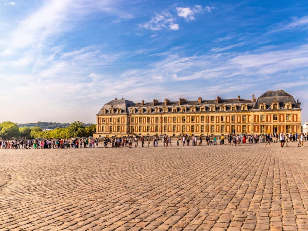 large stone courtyard in front of palace of versailles