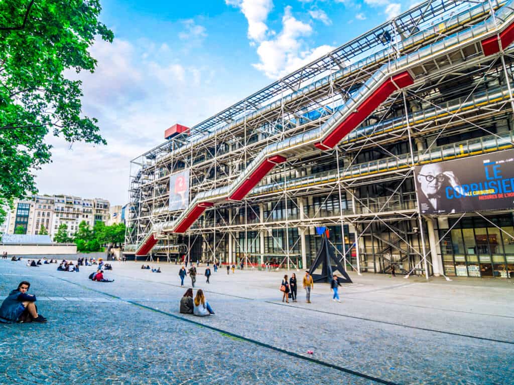 people sitting under trees looking at exterior of view from Centre Pompidou paris