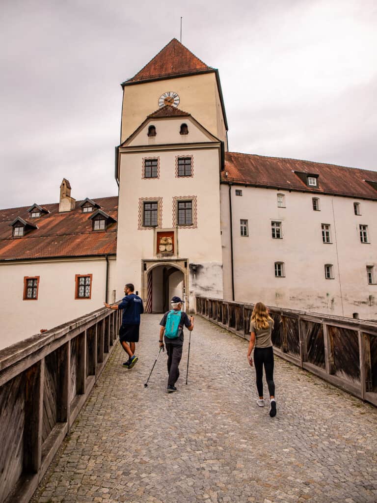 People walking over a bridge towards a fortress