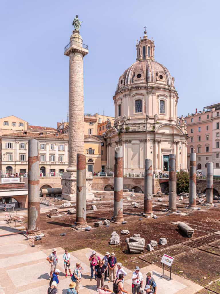 ruins on the side of Via dei Fori Imperiali with domed building and monument in background