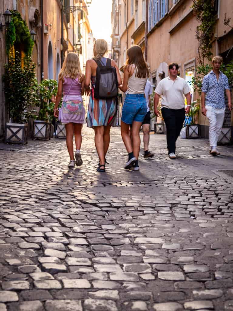 caz and girls walking down cobblestone street in rome
