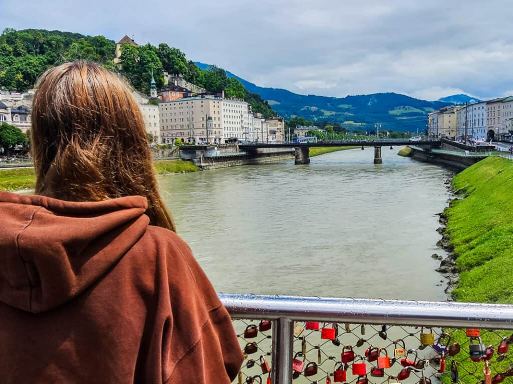 Girl overlooking a river and bridge with mountains in the background
