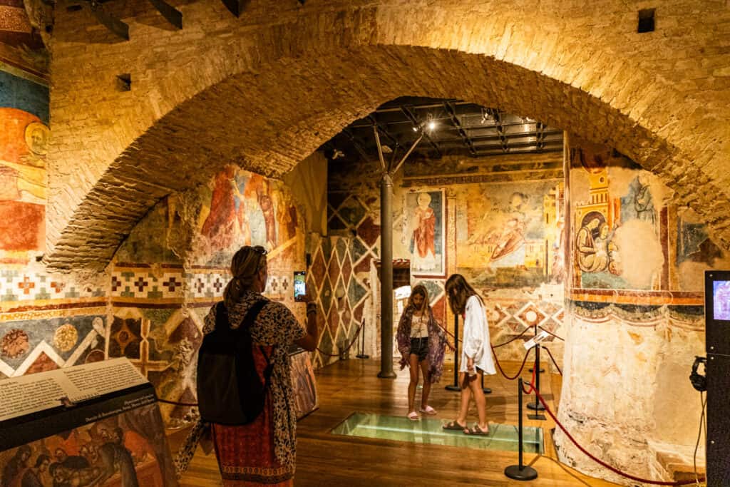 person looking at the colorful frescoes on the crypt walls