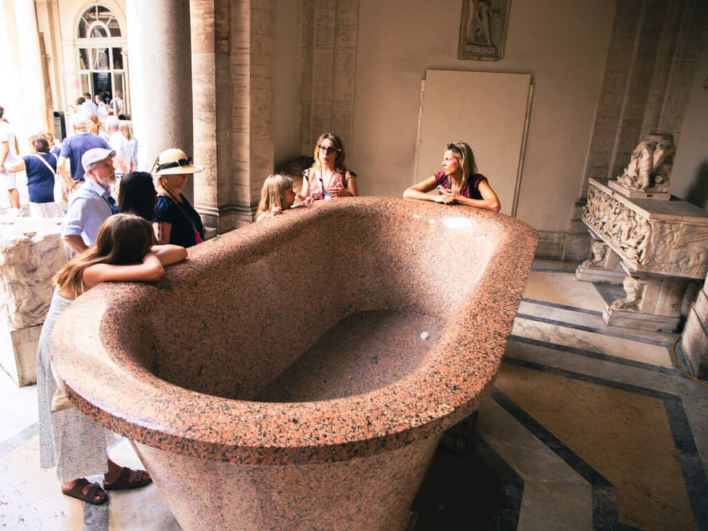 people standing around gigantic marble bath listening to tour guide