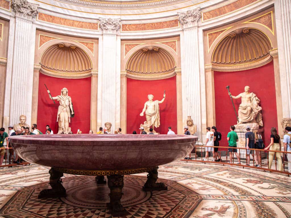 people standing around statues inside vatican