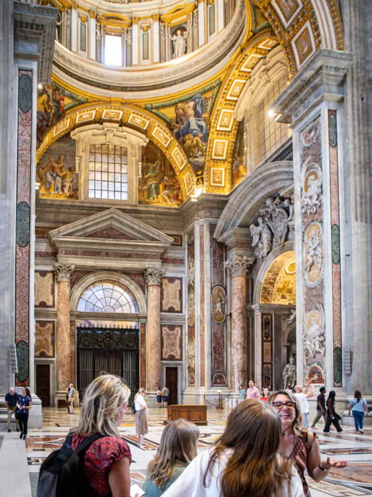 group of people on tour looking at the interior of st peter's basilica