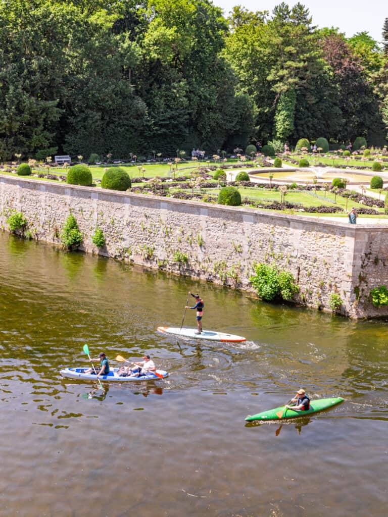 paddle boarders on moat next to palace gardens