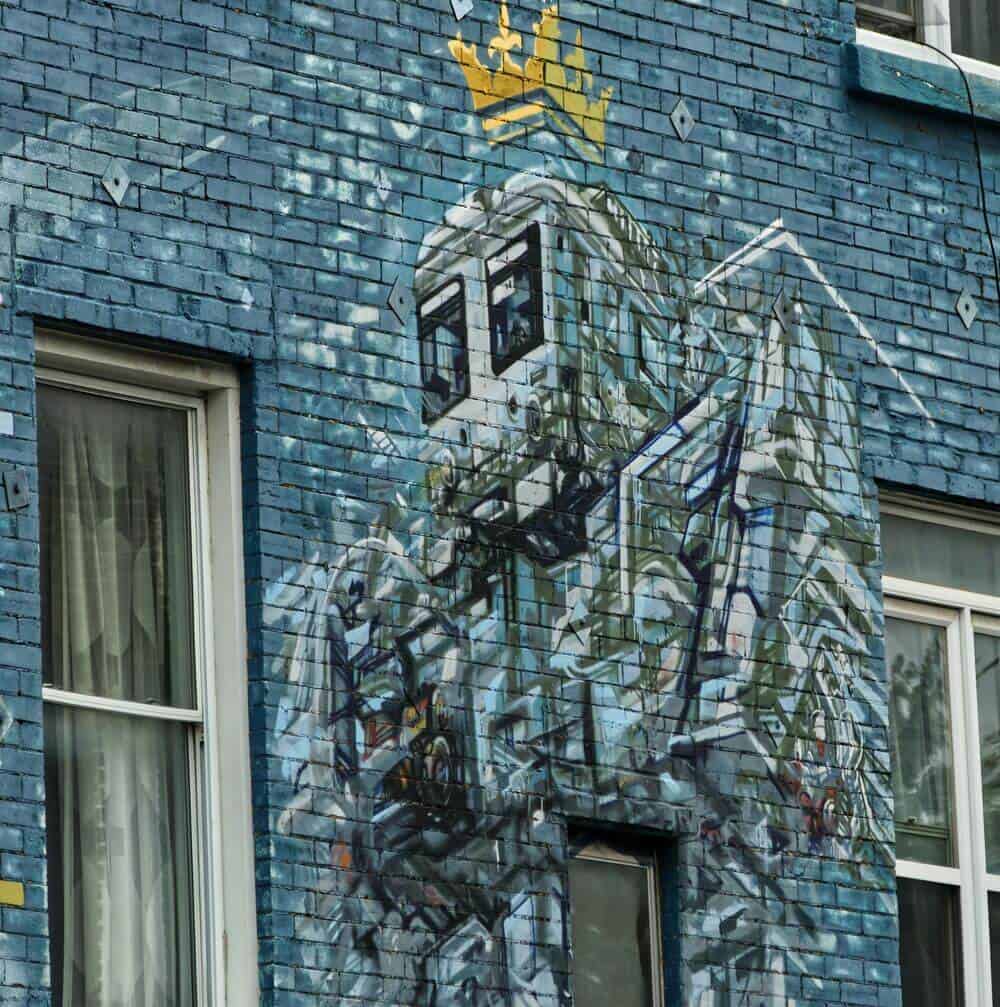 graffiti of robot on blue brick wall