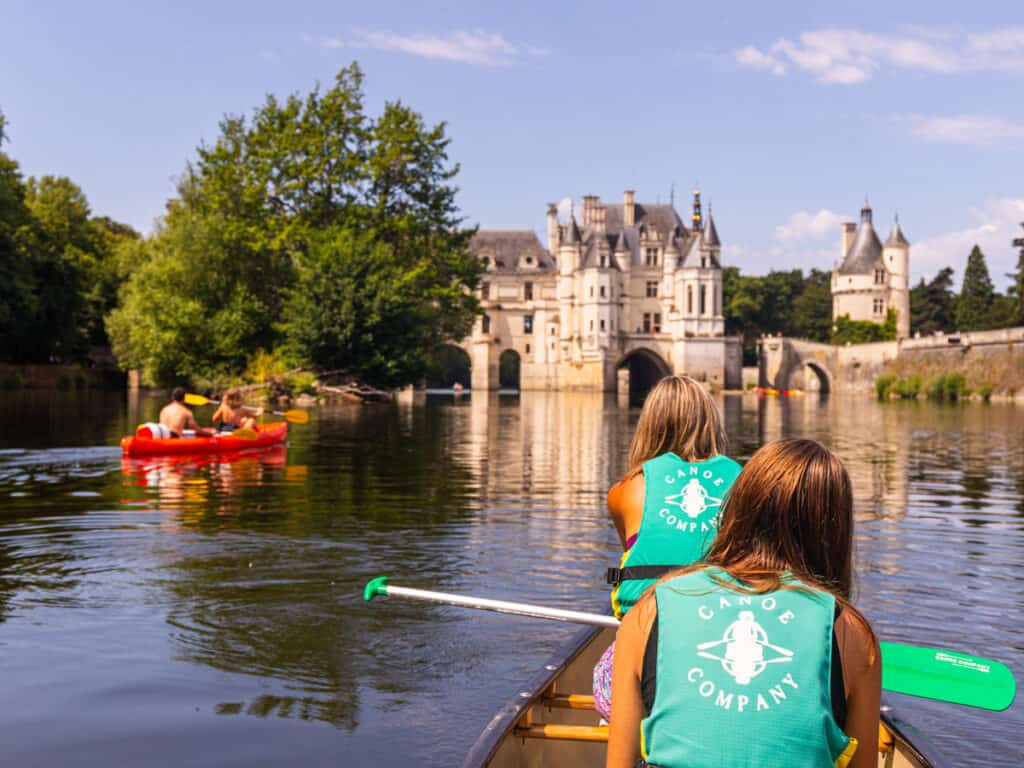 people in canoe paddling up to Château de Chenonceau