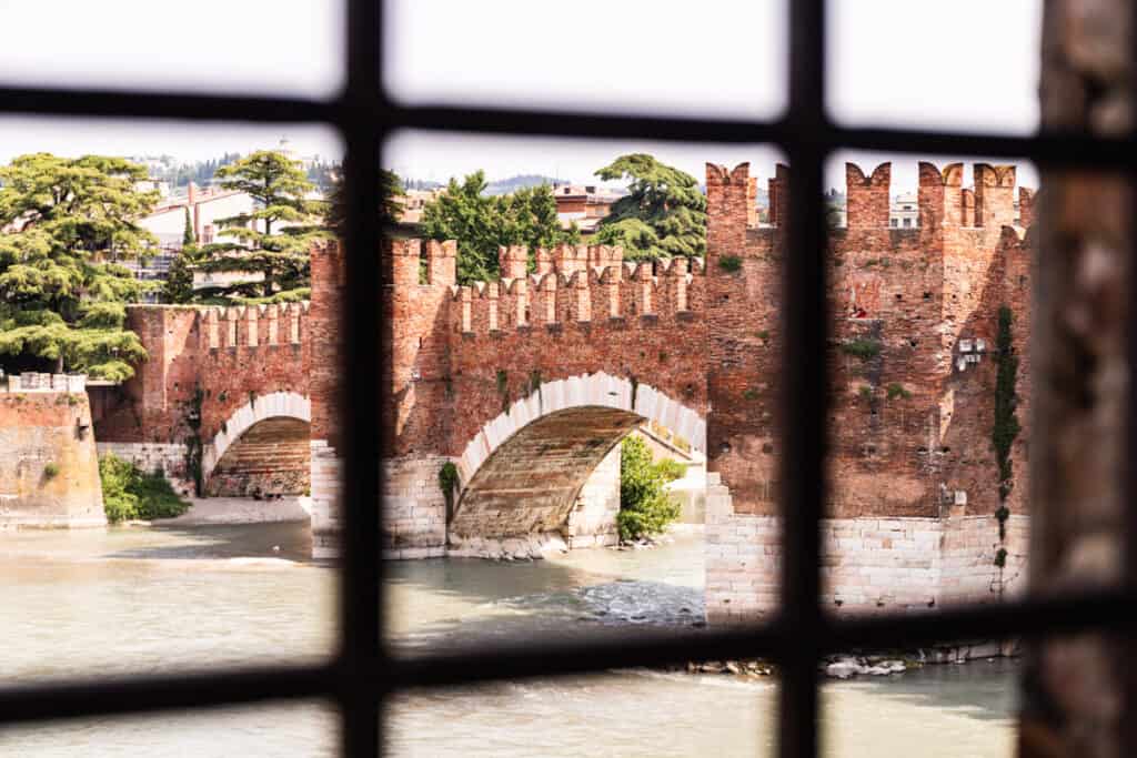 view of castelvecchio bridge from castle behind iron windows