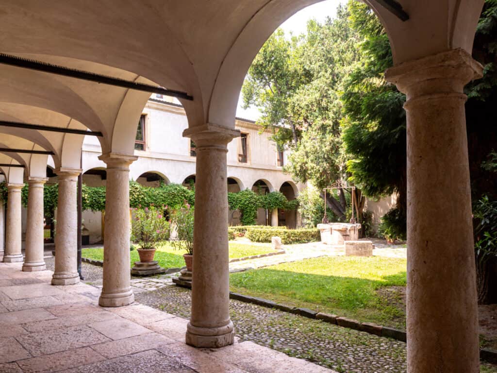 arched columns in walkway surrounding green courtyard