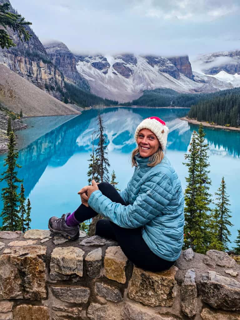 caz sitting on rock wall smiling in front of moraine  lake canada