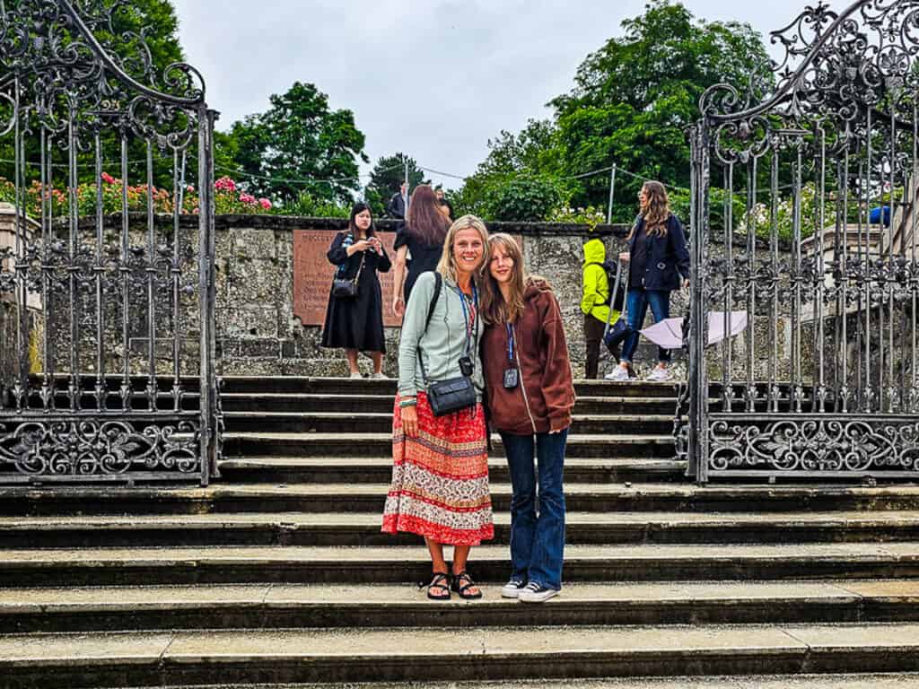 Mom and daughter standing on steps near a gate in Salzburg, Austria