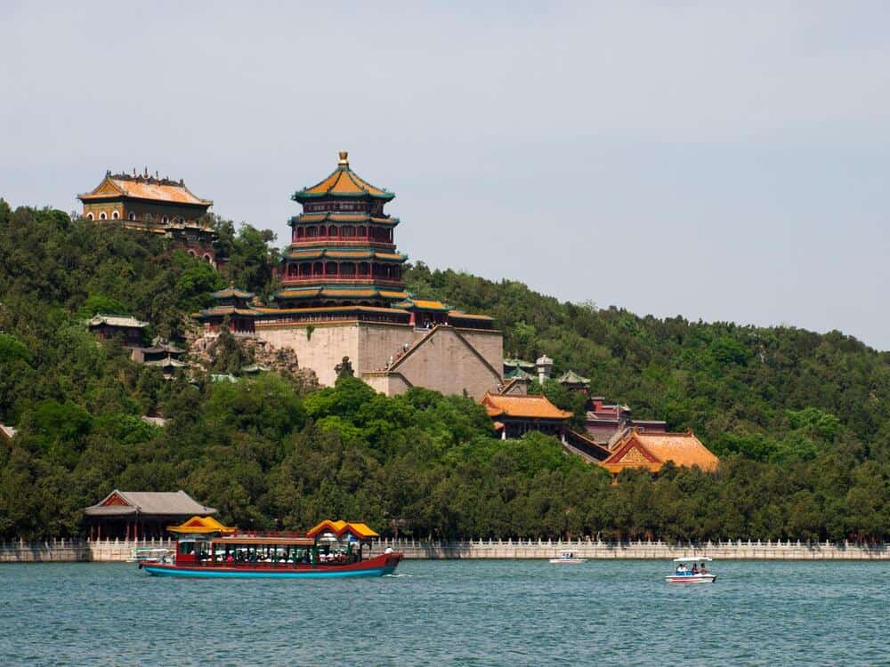 boats in front of The imperial Summer Palace located on a hill in surrounded by trees