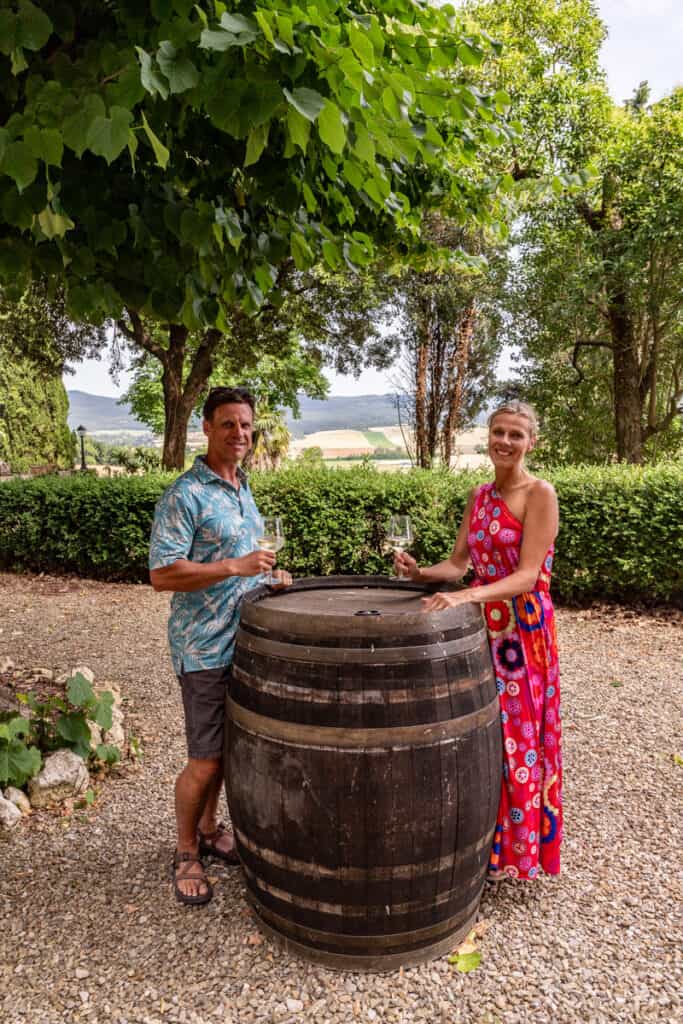 caz and craig drinking on wine barrel under tree
