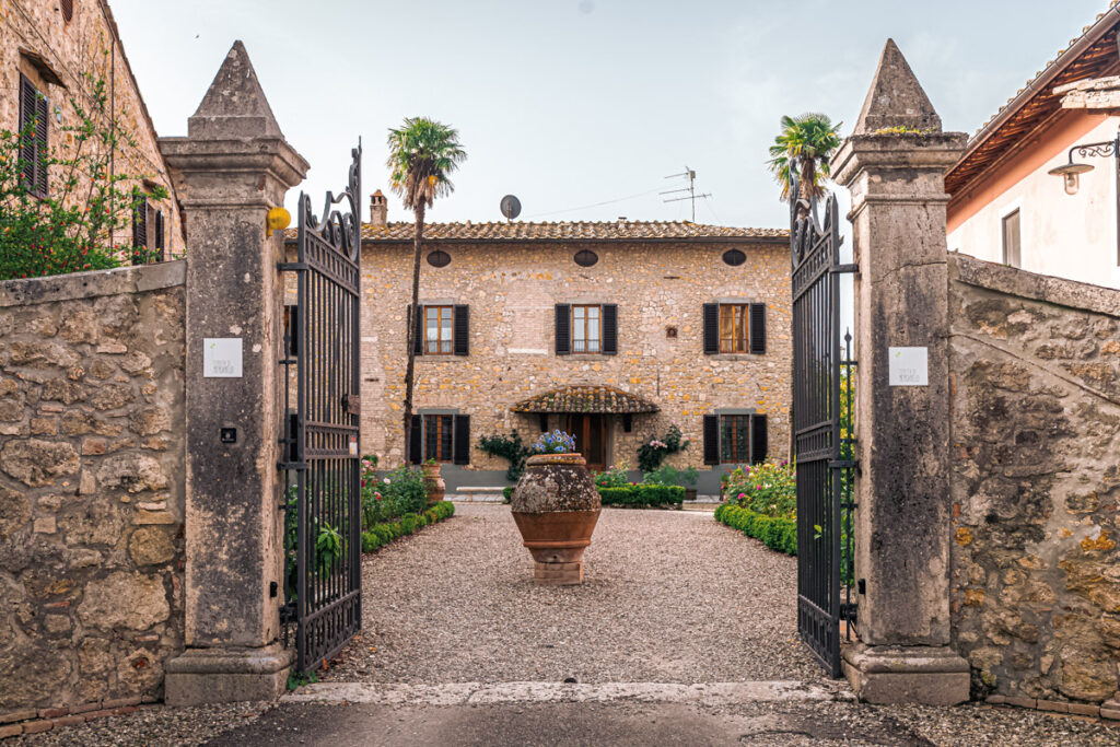 open gates leading to courtyard surrounded by stone buildings in tuscany