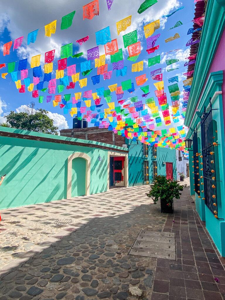 Cobblestone street with colorful flags hanging above it
